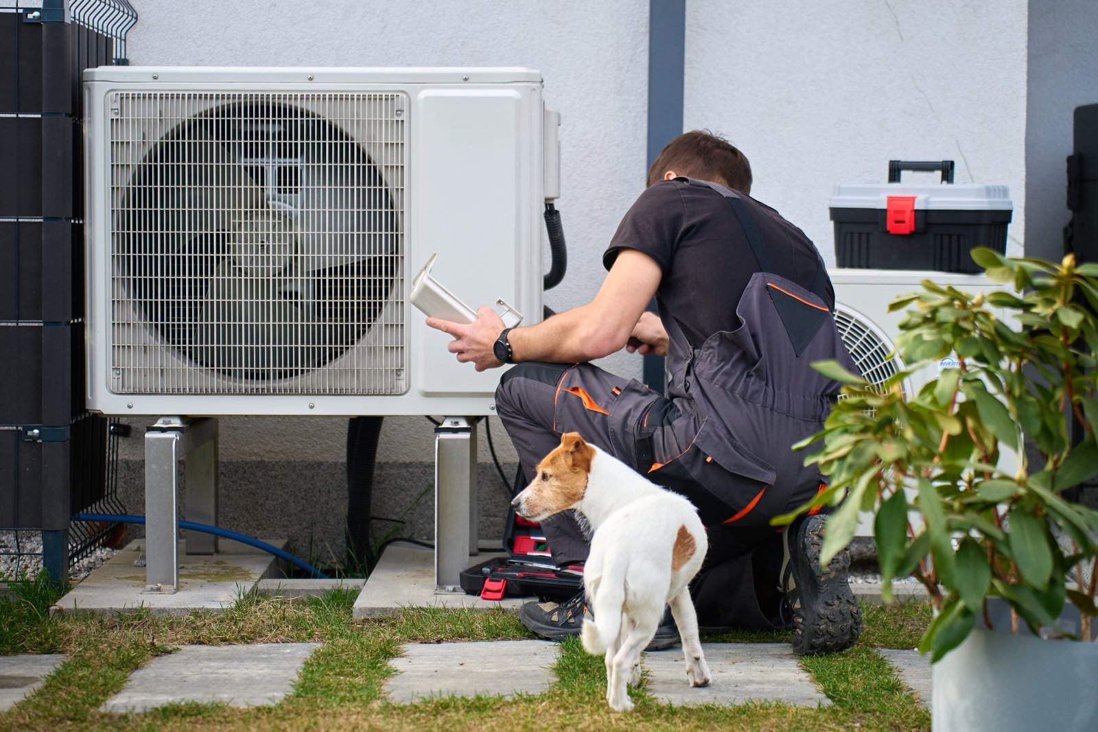 Residential HVAC technician servicing a heat pump unit outside a home